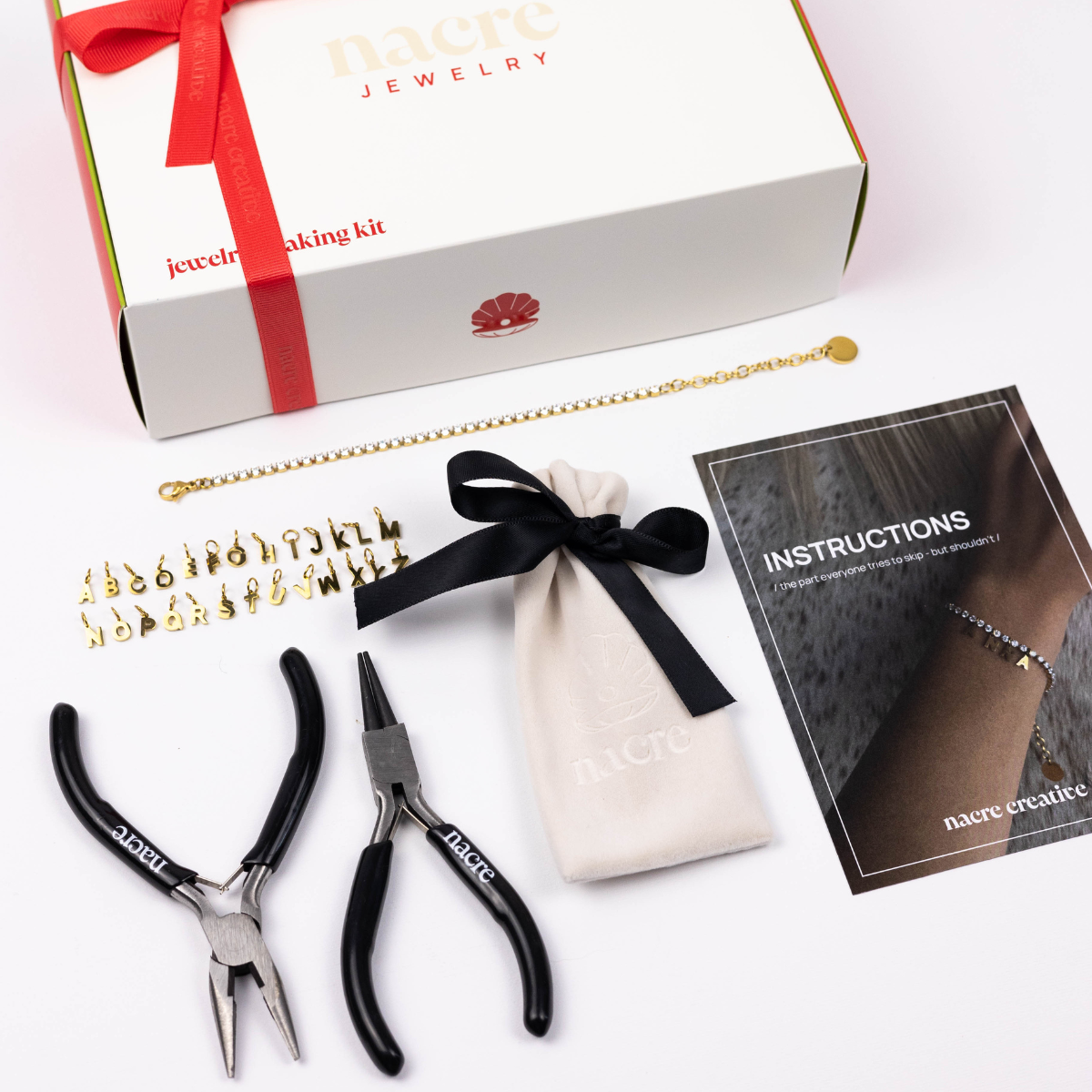 DIY tennis bracelet making kit by Nacre Creative with gift box, gold-plated bracelet, alphabet charms, pliers, velvet pouch, and instruction guide.