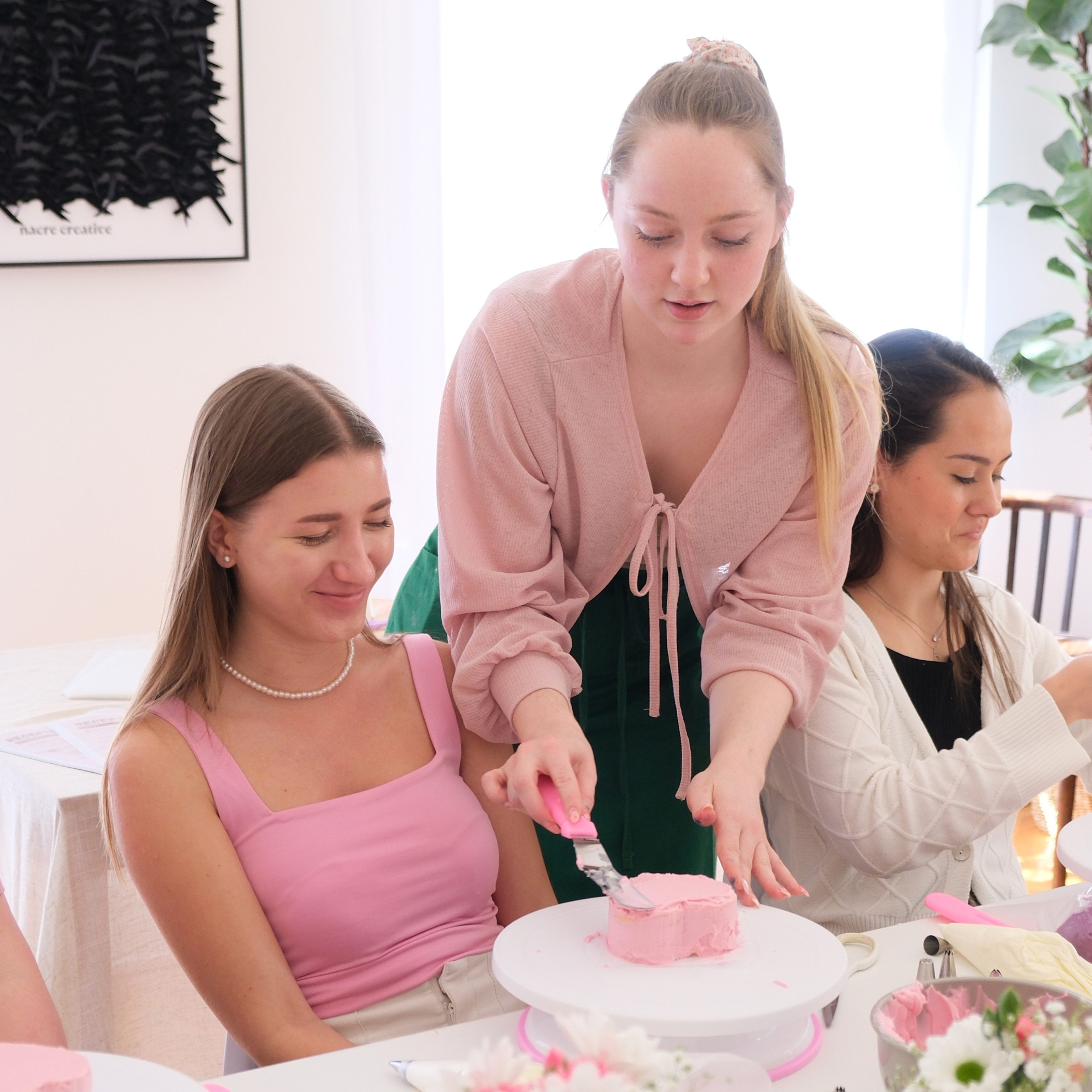 The facilitator demonstrates the proper cake decorating technique to the other participants.