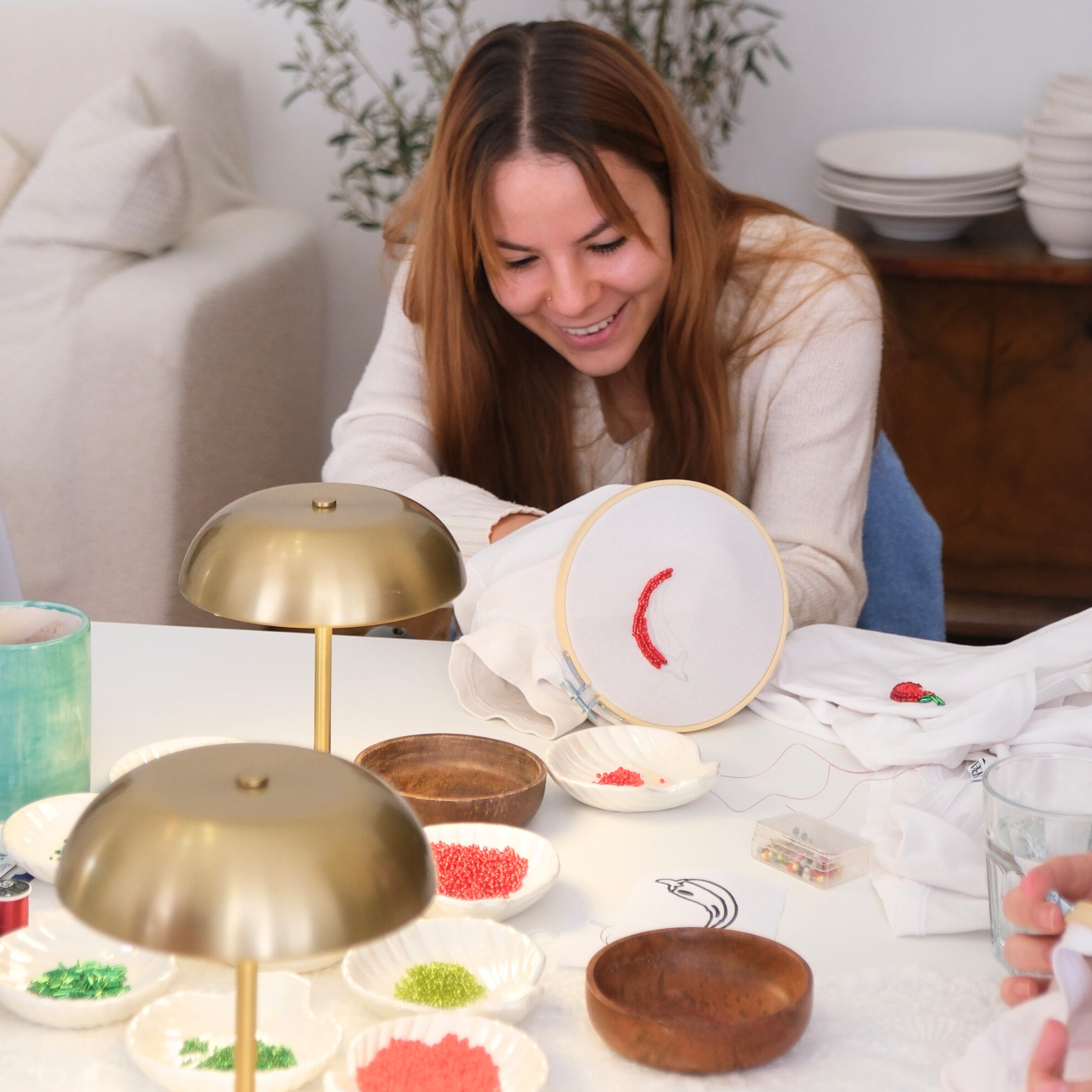 Pretty woman embroidering a chili pattern on a white t-shirt during a creative workshop