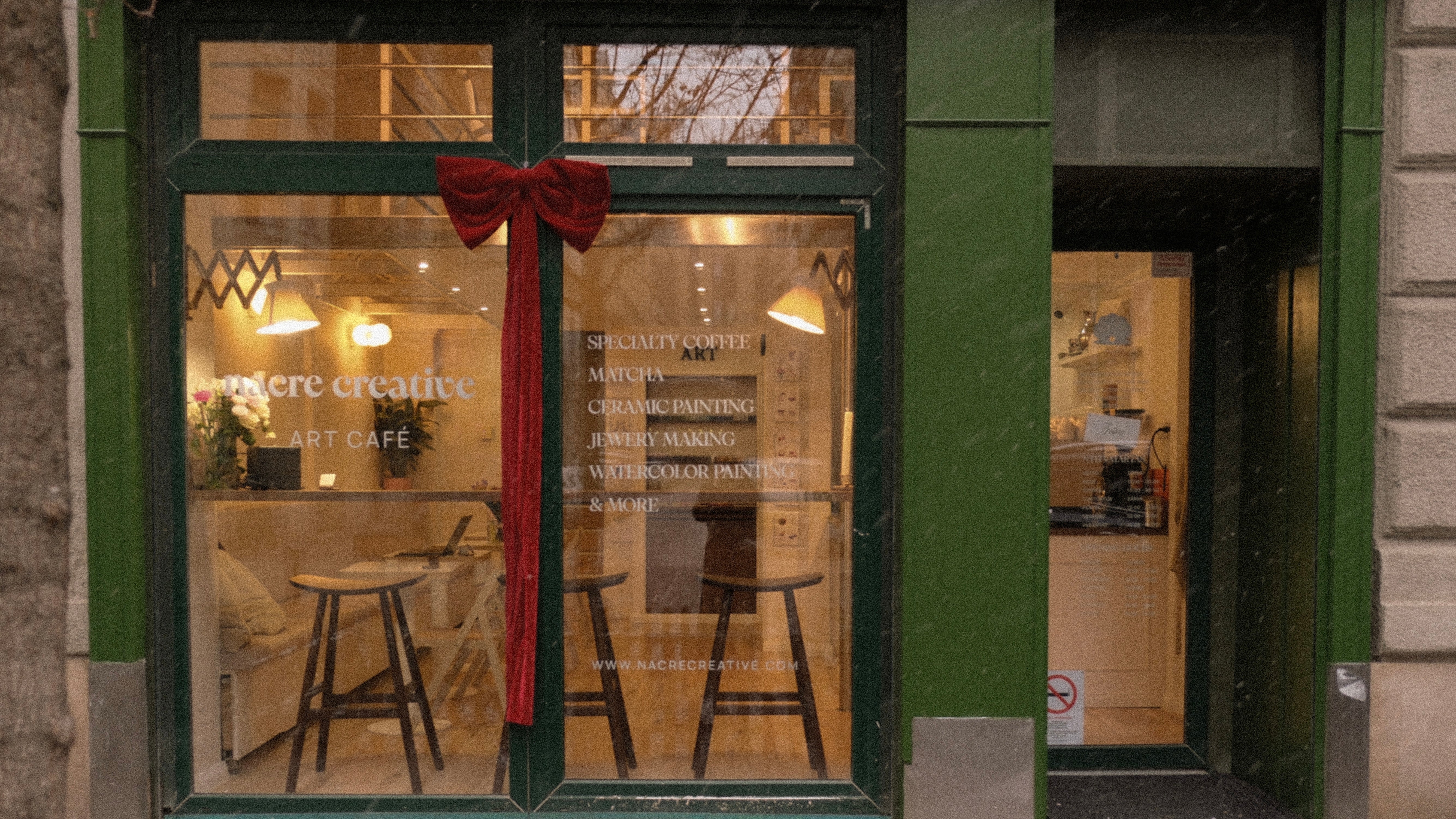 Storefront window with a red bow, showing interior of a café.
