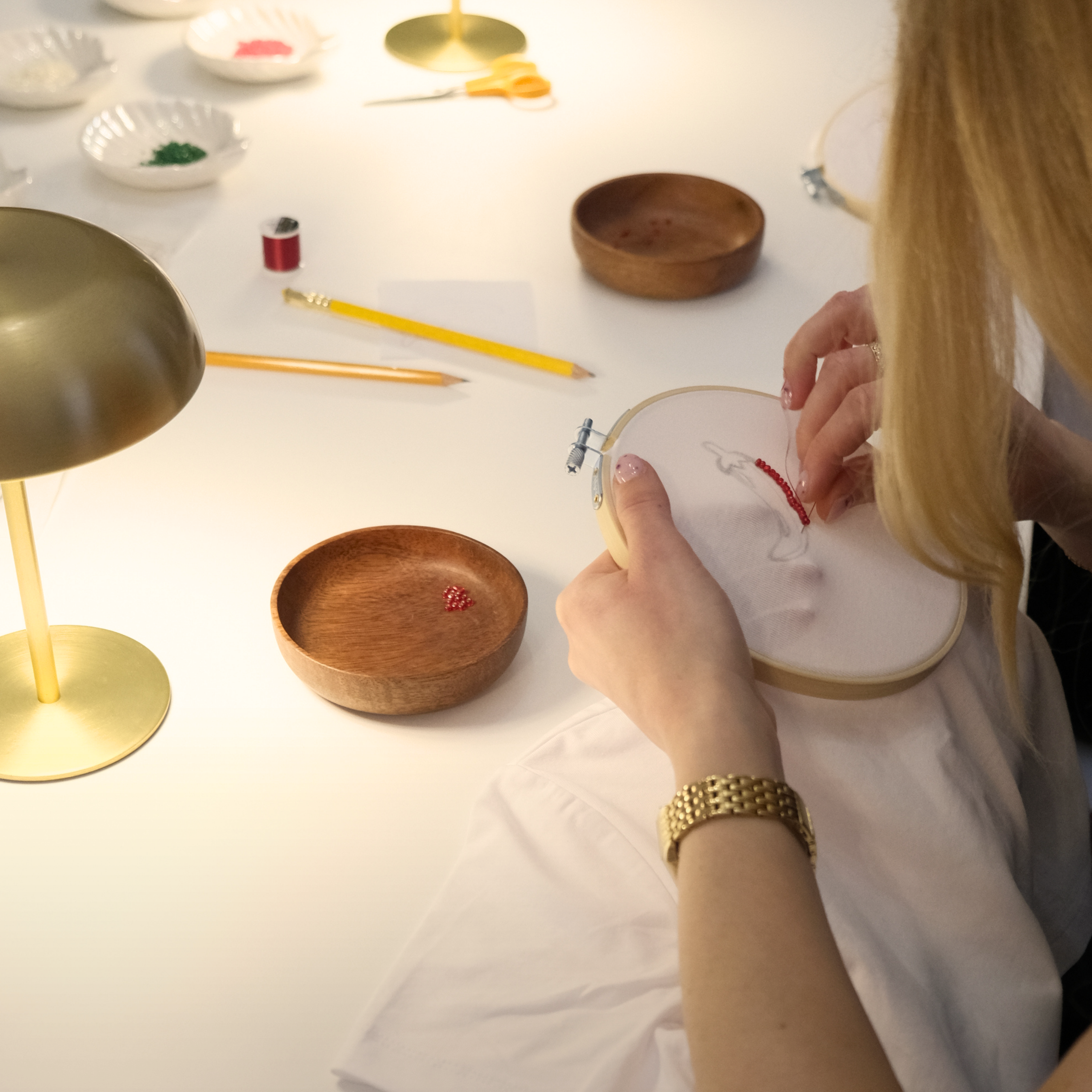 Person embroiderying on a white surface with various tools and materials.