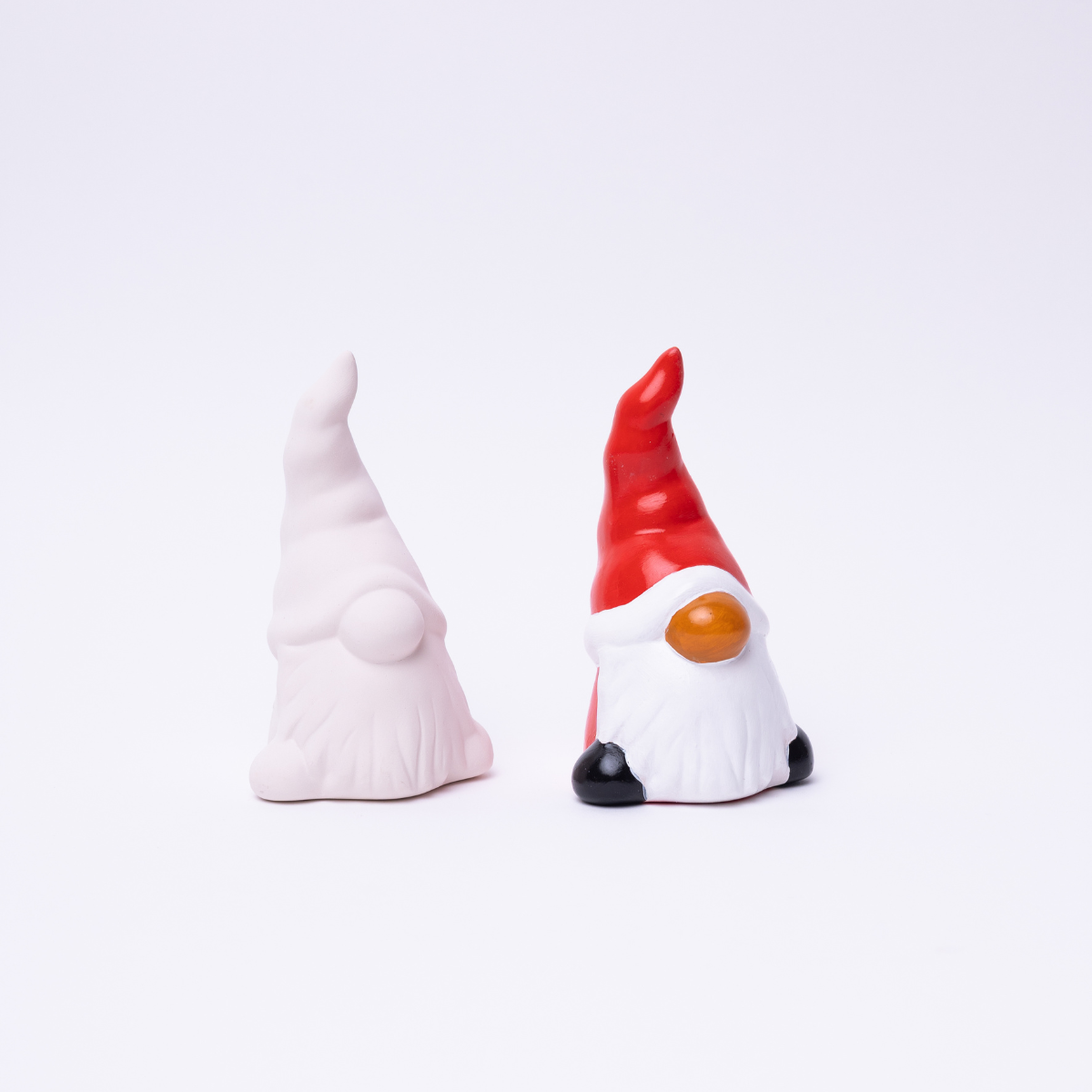 Two Santa Claus figurines, one with a red hat and yellow nose, the other with a white hat, on a light gray background.